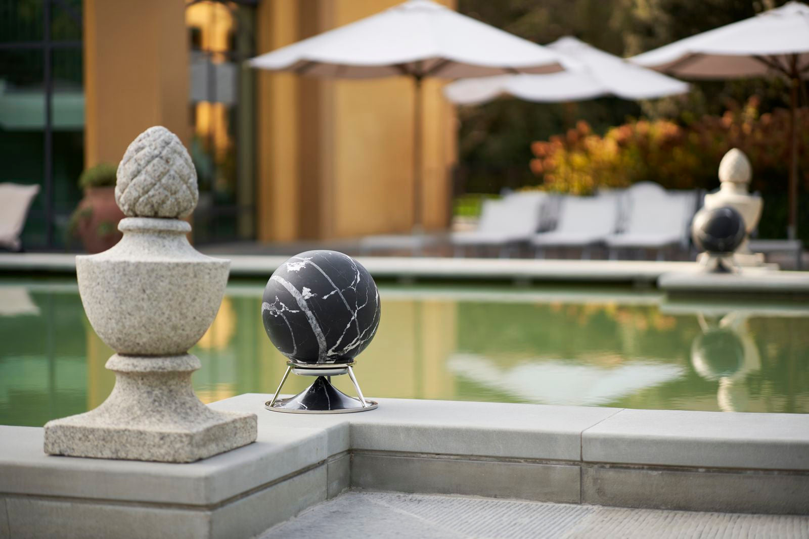 Detaliu de textură minerală pe o boxă din piatră naturală langa o piscina architettura sonora